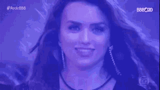 a close up of a woman 's face with her hair blowing in the wind and a purple background .