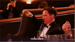 a man in a tuxedo is sitting at a table with a glass of wine and a bottle of water .