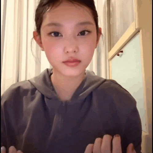 a young girl wearing a gray hoodie is looking at the camera