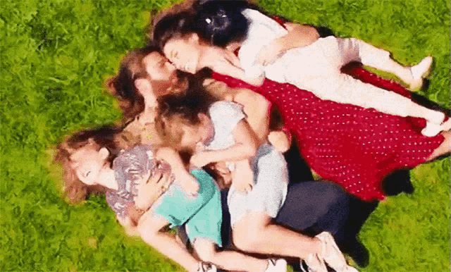 a group of people are laying on the grass hugging each other