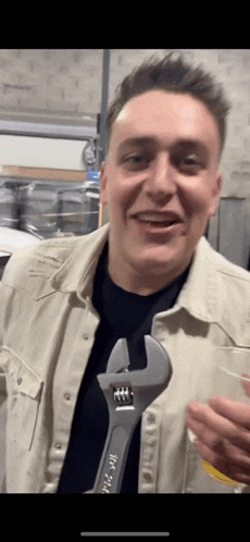 a man in a tan shirt is holding a wrench