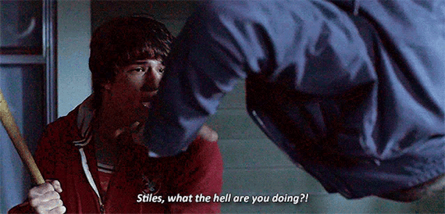 a man is holding a bat and talking to another man who is holding a bat .