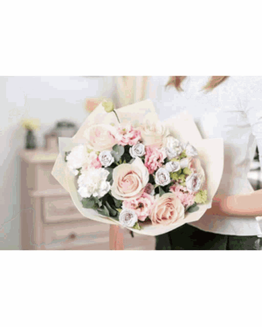 a woman is holding a bouquet of red roses