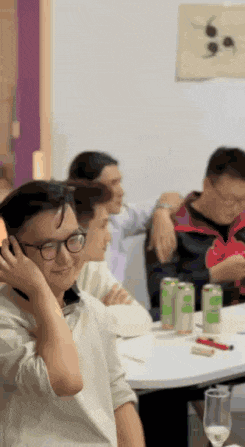 a group of people are sitting around a table with cans of soda on it .