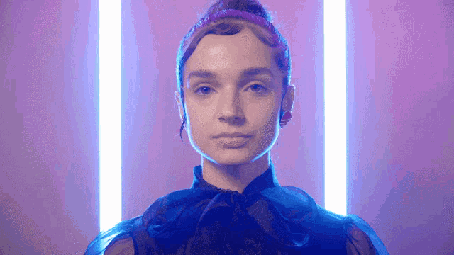 a woman in a black dress is standing in front of a purple background
