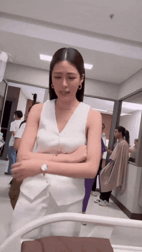 a woman in a white top and white pants is standing in a hospital hallway