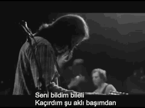 a black and white photo of a man playing a guitar with the words seni bildim bileli in the corner