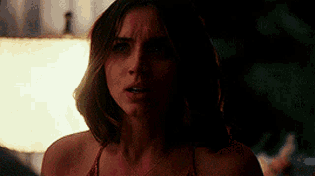 a woman in a red bikini is standing in a dark room looking at the camera .