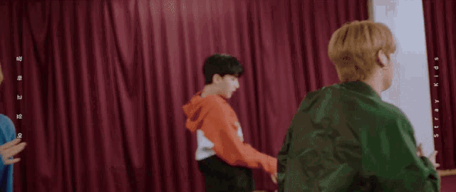 a man in a green jacket is dancing with two other men
