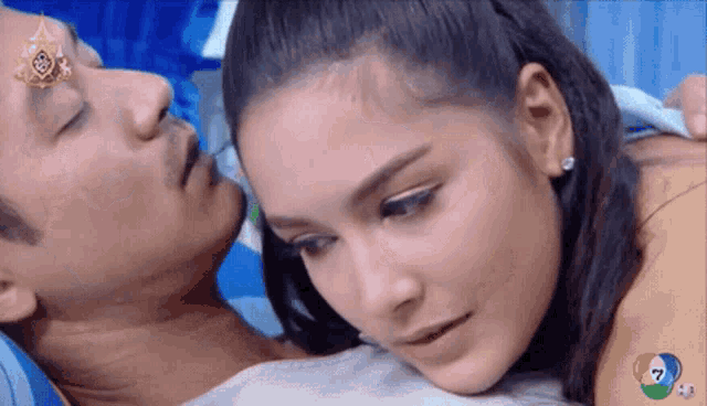 a woman laying on a man 's chest with the number 7 on the bottom left
