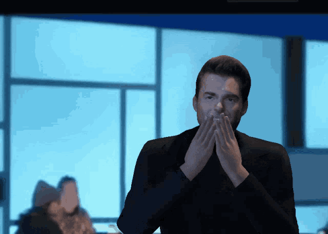 a man covering his mouth with his hands while a woman looks on