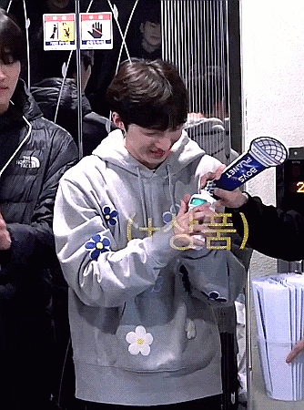a man wearing a hoodie with flowers on the sleeves is being interviewed