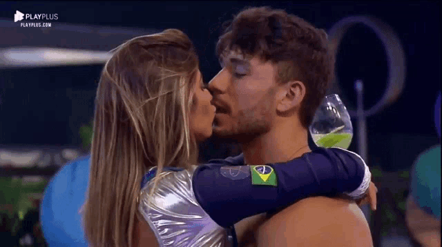 a man and a woman are kissing in front of a playplus sign