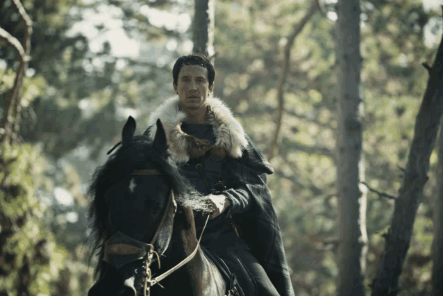 a man wearing a fur cape is riding a black horse in the woods