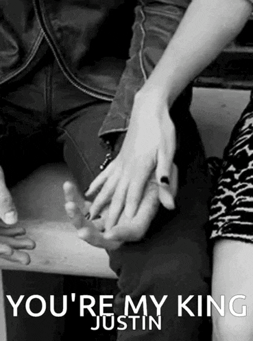 a black and white photo of a man and woman holding hands with the caption " you 're my king justin " .