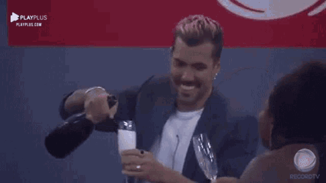 a man is pouring champagne into a glass while a woman looks on .