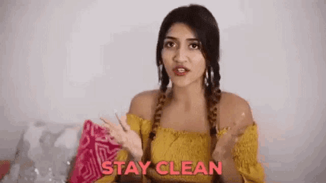 the woman is wearing a yellow off the shoulder top and braids .