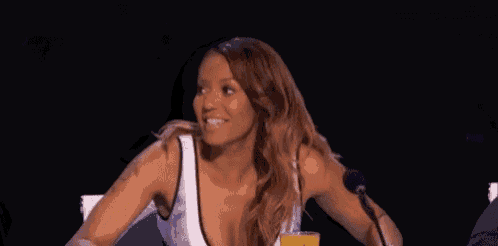a woman is sitting at a table in front of a microphone with her hands outstretched .