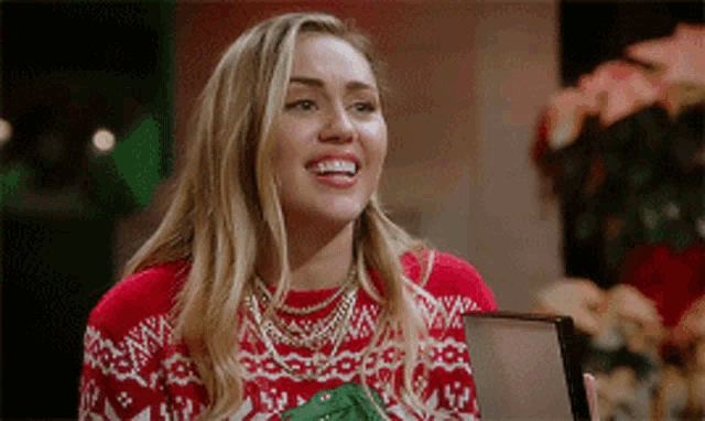 a woman wearing a red sweater is smiling and looking at the camera