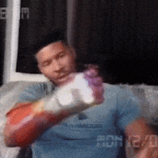 a man wearing boxing gloves is sitting on a couch holding a bottle