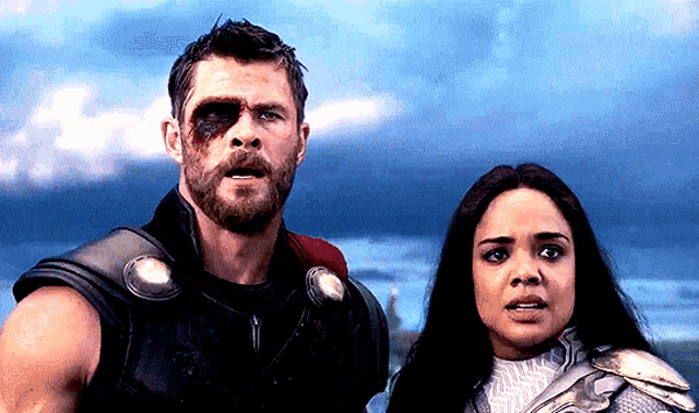 a man and a woman are standing next to each other looking at something .