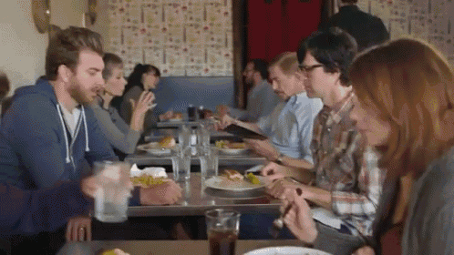 a group of people sitting at tables in a restaurant eating