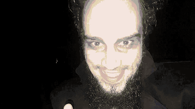 a man with a beard and makeup on his face smiles