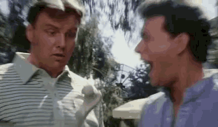 two men are standing next to each other and talking .