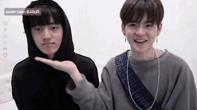 two young men are standing next to each other and one is wearing a hoodie and the other is wearing a gray sweatshirt