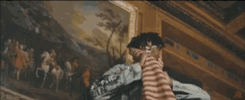 a man in a red and white striped shirt is sitting on a ledge