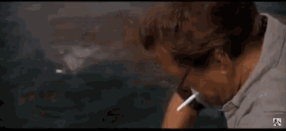 a man is smoking a cigarette in front of a shark in the water .