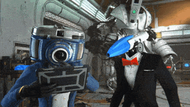 two robots with cameras on their heads are standing next to each other in a room
