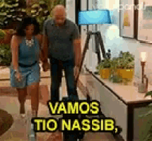 a man and a woman are walking in a living room with a sign that says vamos tio nassib