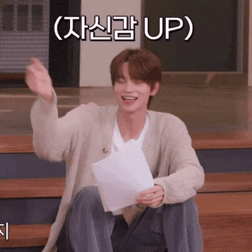 a young man is sitting on a set of stairs holding a piece of paper and smiling with the word up written above him
