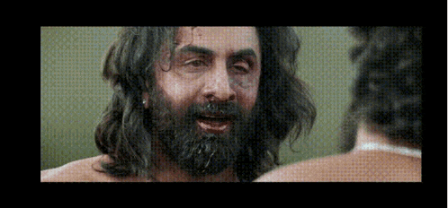 a man with long hair and a beard is looking at another man .