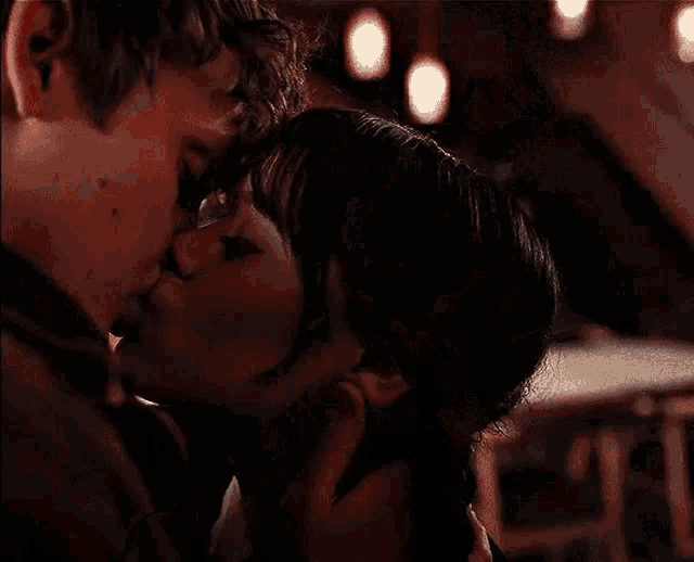a man and a woman are kissing in a dark room in a restaurant .