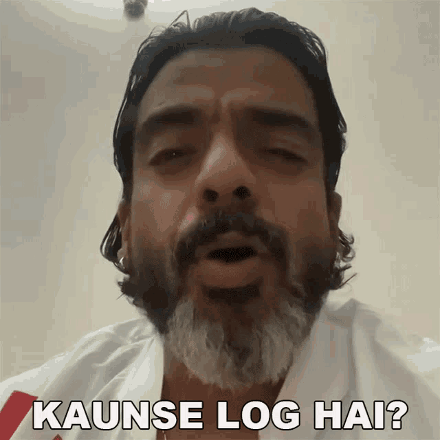 a man with a beard is wearing a white shirt and says kaunse log hai