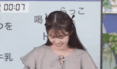 a young woman is smiling in front of a white board with chinese characters .