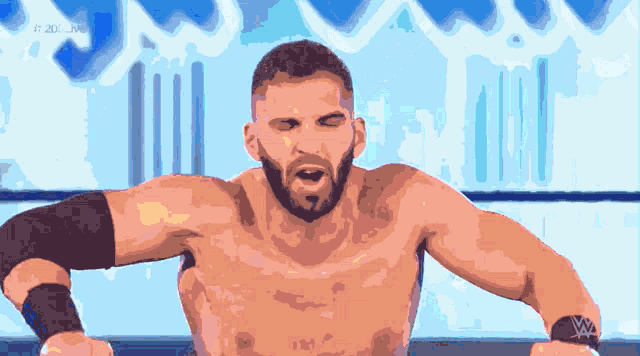 a shirtless wrestler with a w logo on his arm stands in a ring