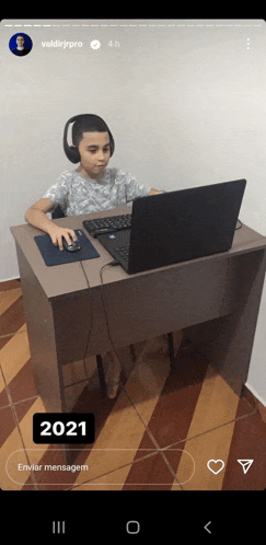 a young boy wearing headphones is sitting at a desk with a laptop