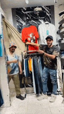 two men are standing in front of a clothing rack in a clothing store .