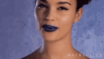 a close up of a woman 's face with blue lipstick on her lips .