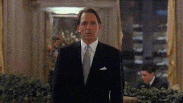 a man in a suit and tie is standing in front of a window with a sign that says ' abc ' on it