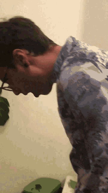 a man wearing glasses and a tie dye shirt looks down