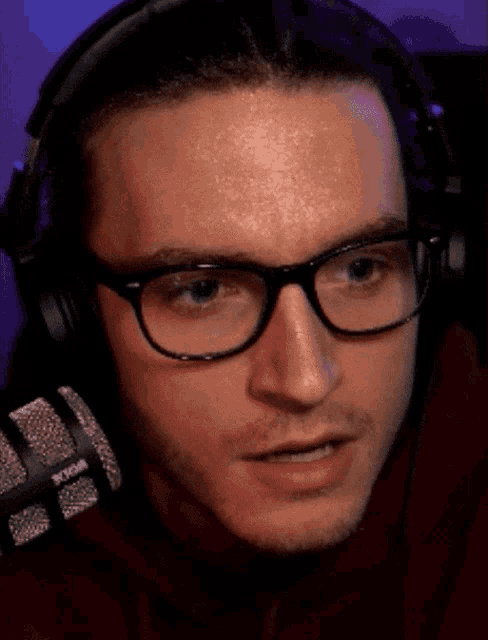 a man wearing glasses and headphones looks at the camera