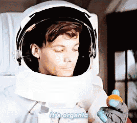 a man in a space suit is holding a stuffed animal and says it 's organic