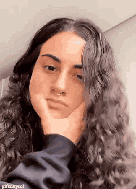 a woman with long curly hair and a nose ring