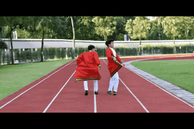 two people walking on a track wearing red jackets