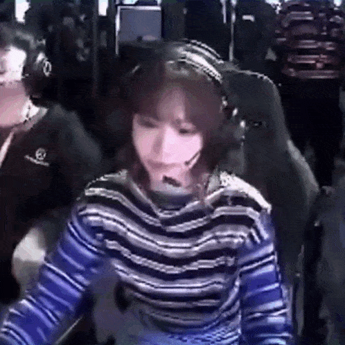 a woman wearing headphones and a striped shirt is sitting in front of a computer screen .