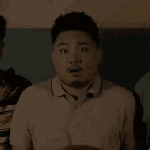 a man with a beard is making a surprised face while standing in a room .